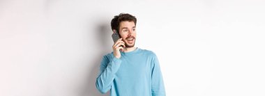 Teknoloji konsepti. Neşeli bir adam cep telefonuyla konuşuyor, telefonla konuşuyor ve eğleniyor gibi görünüyor, beyaz arka planda duruyor..