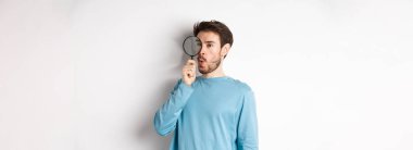 Meraklı adam sağ logodaki büyüteçten bakıp 