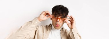 Çekici bir delikanlının yakın plan fotoğrafı. Havalı bir şeye bakıyor. Gözlüklerin altına bakıyor ve hayret verici diyor..