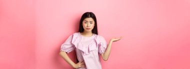 Ne olmuş, kimin umurunda. İlgisiz ve şüpheci Asyalı kız kolunu kaldırıyor ve kameraya rahatsız edilmeden bakıyor, yanlış olan ne anlamıyorum, pembe arka planda duruyor..