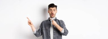 Reklam göstermekten heyecan duyan, parmaklarını sağa doğru gösteren, hayretler içinde kalan, beyaz arka planda duran, özel bir anlaşma yapan adam..