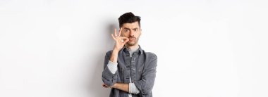 Ciddi adam fermuar hareketi yapıyor, çenesini kapalı tutmasını söyle, kaşlarını çatsın ve dudaklarını mühürlesin, beyaz arka planda dursun..