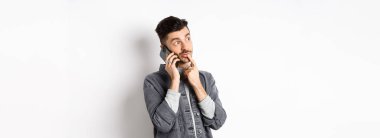 Düşünceli yakışıklı bir adamın telefon konuşması ve düşünme şekli, dışarıdan sipariş verirken seçim yapması, beyaz arka planda durması..