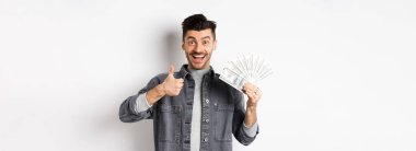 Dolarları tutan heyecanlı bir adam resmi ve mutlu yüzlü, para kazanan, beyaz arka planda duran,.