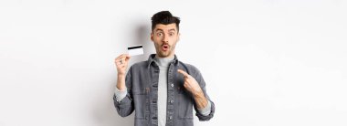 Vay canına, şuna bak. Heyecanlı adam plastik kredi kartını işaret ediyor ve beyaz arka plana karşı duran harika bir anlaşmayla şaşırmış görünüyor..