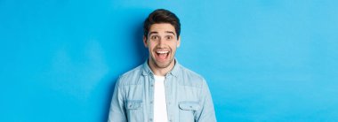 Heyecanlı bir adamın, fotokopi alanı için mavi arka planda duran hayret verici bir şeye baktığı yakın plan..