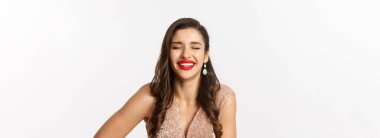 Yeni yıl kutlaması ve kış tatili kavramı. Kırmızı dudaklı zarif bir kadın, gülüyor ve mutlu görünüyor, beyaz arka planda duruyor..