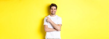 Çekici bir gencin, sarı arka planda duran reklam ya da afişi gösteren, fotokopi alanını işaret etmesi..