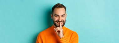 Yakışıklı, gülümseyen, sessiz, sırlarını açıklayan, açık mavi arka planda duran adamın yakın çekimi..