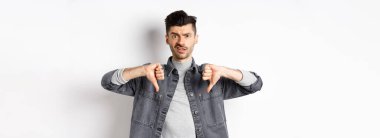 Hayal kırıklığına uğramış bir adam beyaz arka planda duran, kötü bir şeye şüpheyle bakan, hoşlanmayan ve onaylamayan bir adam..