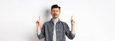 Üzgün ve sefil bir adam ağlarken parmaklarını havaya kaldırıyor, hayal kırıklığına uğramış reklamlar yapıyor, hıçkıra hıçkıra ağlıyor, beyaz arka planda duruyor..