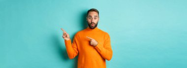 Reklam veren, pankartı işaret eden, turkuaz arka planda duran harika bir adam..