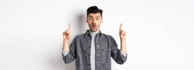 Heyecanlı adam reklam teklifini kontrol ediyor, şaşırıyor ve parmaklarını havaya kaldırıyor, havalı bir duyuru yapıyor, beyaz arka planda duruyor..