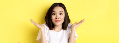 Aptalca bir hata. Yakışıklı Asyalı kızın özür dileyip, omuzlarını silkip, sırıtarak sarı arka planda durduğu bir sahne..