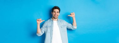 Kendine güvenen bir adamın portresi, profesyonel olmak, mavi arka planda dikilirken böbürlenmek..