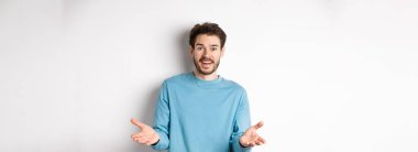 Yakışıklı genç adam senin için mutlu hissediyor, kameraya el kaldırıyor ve iyi işi övüyor, tebrik ediyor, beyaz arka planda duruyor..