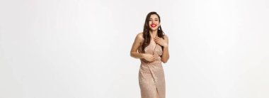 Parti ve kutlama konsepti. Zarif elbiseli, uzun boylu güzel bir kadın Noel hediyelerinin yanında duruyor, mutlu bir şekilde gülüyor, beyaz arka planda duruyor..