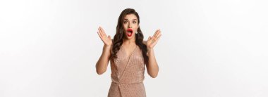 Kış tatili Gece elbisesi ve makyajlı güzel bir kadın, kameraya şaşırmış ve etkilenmiş görünüyor, yeni yıl tanıtım teklifine bakıyor, beyaz arka plan.