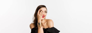 Nişan yüzüğüyle gösteriş yapan güzel bir kadının yakın çekimi, elini gösteriyor ve gülümsüyor, beyaz arka planda dikiliyor..