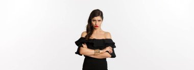 Moda ve güzellik. Şirin somurtkan kız arkadaş, alınının altından kollarını kavuşturmuş, kızgın, beyaz arka planda duruyor..