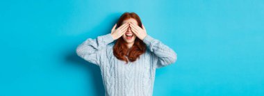 Neşeli kızıl saçlı manken gözlerini kapar ve Noel hediyesini bekler. Yüzünde el ele tutuşur, eğlenir, şaşırır, mavi arka planda durur..