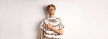 Genç sakallı, kızıl saçlı, kalbi olan, vatansever görünen, milli marş boyunca ayakta duran, beyaz arka planda duran bir adam..