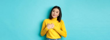 Yürekten güzel bir kadının portresi, kalp üzerinde el ele tutuşan, gülümseyen ve şefkatle dinleyen, mavi arka planda duran, sarı kazaklı..