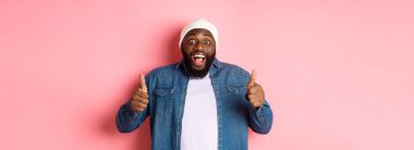 Etkilenmiş Afrikalı-Amerikalı hippi adam onaylıyor, onaylıyor ve teklif ediyor, harika bir seçim, pembe arka planda duruyor..