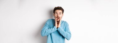 Yakışıklı adamın görüntüsü soluk soluğa kaldı ve kameraya baktı. Şaşırdı, müthiş tanıtım tekliflerine baktı, beyaz arka planda durdu..