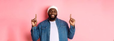 Yakışıklı, mutlu, Afro-Amerikalı bir adam. Parmakla işaret ediyor, gülümsüyor ve tanıtım teklifi sunuyor. Hippi beresi ve kot gömlek giyiyor..
