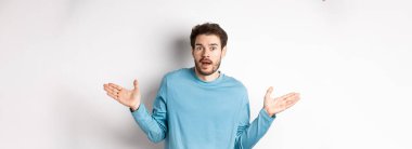 - İnanılmaz. İnançsızlıkla bakan, ellerini yana açmış, etkilenmiş, beyaz arka planda duran genç adam..