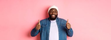 Mutlu Afro-Amerikalı adam onay veriyor. İyi bir şey gibi. Pembe arka planda duran, övgüler yağdırıyor..