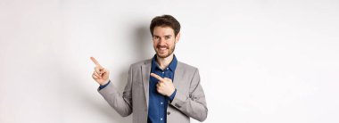 Takım elbiseli yakışıklı adam sağ üst köşeyi işaret ediyor. Logoyu, reklam şirketini gösteriyor. Beyaz arka planda duruyor..