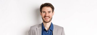 Takım elbiseli, gülen, gülümseyen, beyaz arka planda duran mutlu sakallı adamın yakın çekimi..