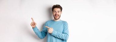 Neşeli gülümseyen adam reklamlar için beyaz alana pankart ya da logo gösteriyor. Ürün öneriyor, stüdyonun arka planında duruyor..