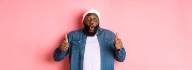 Etkilenmiş Afrikalı-Amerikalı hippi adam onaylıyor, onaylıyor ve teklif ediyor, harika bir seçim, pembe arka planda duruyor..