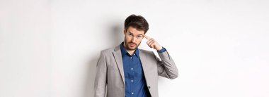 Sinirli erkek işverenin azarlaması, başını işaret etmesi, aklını mı kaçırdın sen? Alnının altından kameraya bakıyorsun, beyaz arka planda takım elbise içinde duruyorsun..