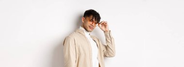 Yakışıklı adam seni selamlıyor, göz teması kuruyor, küstah sırıtıyor, beyaz arka planda duruyor..