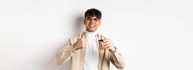 Gerçek insanlar. Kahvesini yudumlayan, kahvesini yudumlayan, kahve öneren, beyaz arka planda duran neşeli, güler yüzlü adam..