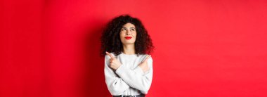 Gülümseyen mutlu bir kadının yüzü yana dönük, kararlı bir şekilde yukarı bakıyor, bir şey seçiyor, kırmızı arka planda verdiği karardan emin duruyor..