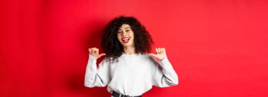 Kırmızı dudaklı, kendine güvenen, kendini beğenmiş, gösteriş meraklısı, kırmızı arka planda duran kendine güvenen genç bir kadın..