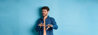 Adam korkunç ve kötü bir şeyden korkup kaçıyor, kötü ofisten reddediyor, tiksinmiş görünüyor, mavi arka planda duruyor. Boşluğu kopyala