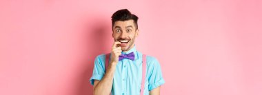 Heyecanlı ve baştan çıkarıcı genç adam bir şey istiyor. Çekicilikle tırnak yemek kameraya bakmak, ürünü seçmek, pembe arka planda dikilmek..