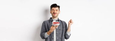 Doğum günün kutlu olsun. Pastada dilek tutan, doğum gününü kutlayan, beyaz arka planda duran çocuk..