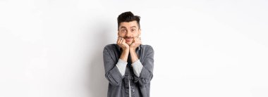 Bıyıklı, tatlı bir genç adam gülümseyen ve kameraya rüya gibi bakan, güzel bir şeye bakan, gerçek güzelliğe hayran olan, beyaz arka planda duran..