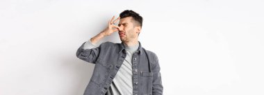 İğrenç adam arkasını döndü ve burnunu kötü kokuya kapattı. İğrenç kokuyordu, beyaz arka planda duruyordu..