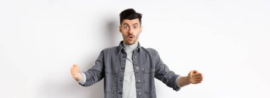 Büyük boyutlarda, büyük nesneleri şekillendiren, beyaz arka planda duran heyecanlı beyaz adam..