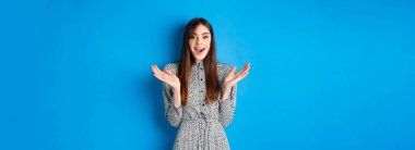 Heyecanlı güzel kadın alkışlıyor ve seni tebrik ediyor, iyi iş çıkarıyorsun, kameraya alkış tutuyorsun ve gülümsüyorsun, mavi arka planda duruyorsun..