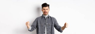 İğrenmiş bir adam büyük bir obje gösteriyor ve nefret ve nefretten yüzünü buruşturuyor. İğrenç, büyük bir şeyden bahsediyor, beyaz arka planda duruyor..