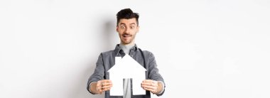 Gayrimenkul ve sigorta konsepti. Adam gazete kupürlerini görünce heyecanlanıyor, ev alıyor, beyaz arka planda duruyor..